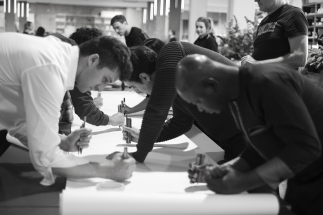 People leaned over a table drawing