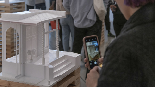 A person pointing a smart phone at a model of a facade