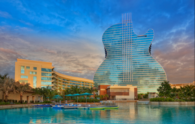 A pool in front of a massive guitar-shaped glass building