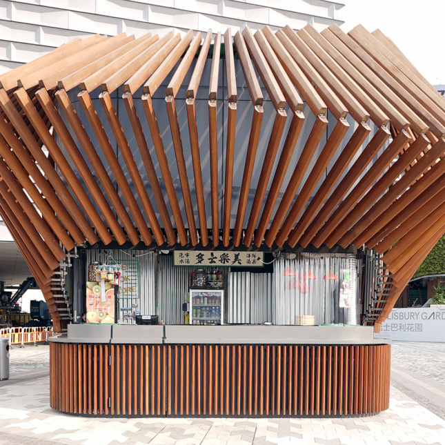 A wooden kiosk topped with an array of wooden elements.