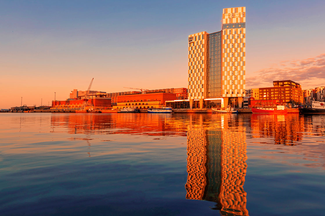 photo of helsinki waterfront during sunset, buildings reflected in the water