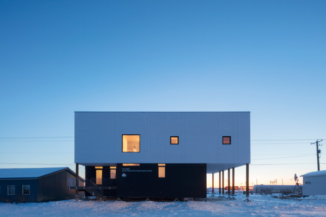 A boxy building in the snow with minimal window coverage