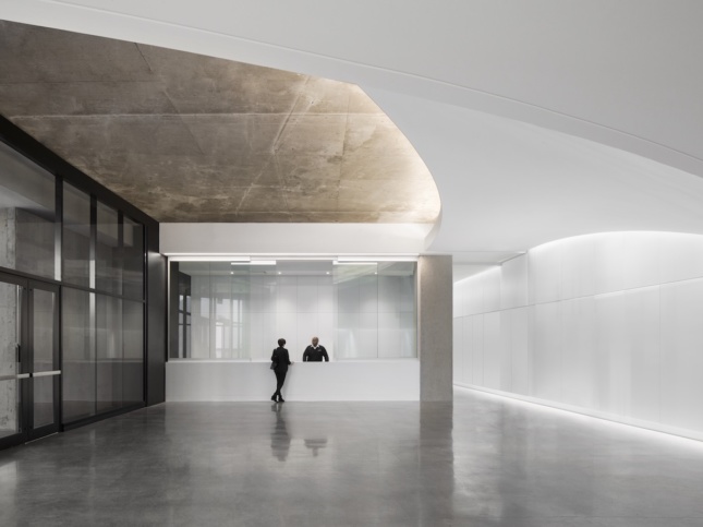 the main entrance at Montreal's renovated Olympic Tower, showing swooping white ceilings meeting exposed concrete slab