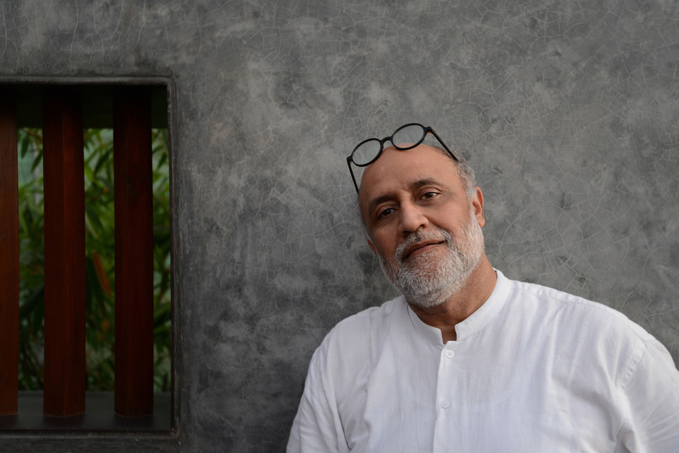 Headshot of a man, Rahul Mehrotra, in a white shirt against a stone wall