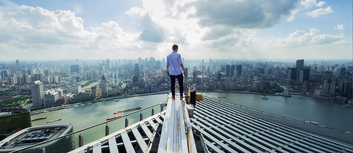 man standing on edge of skyscraper