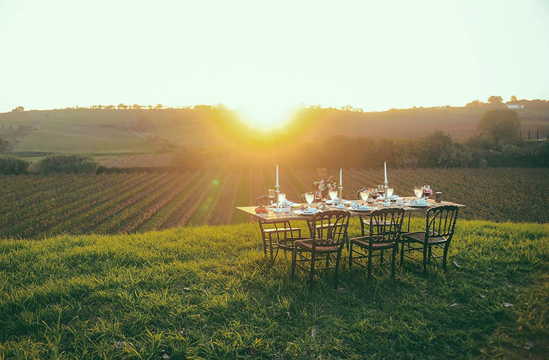 table set overlooking a vineyard during sunset
