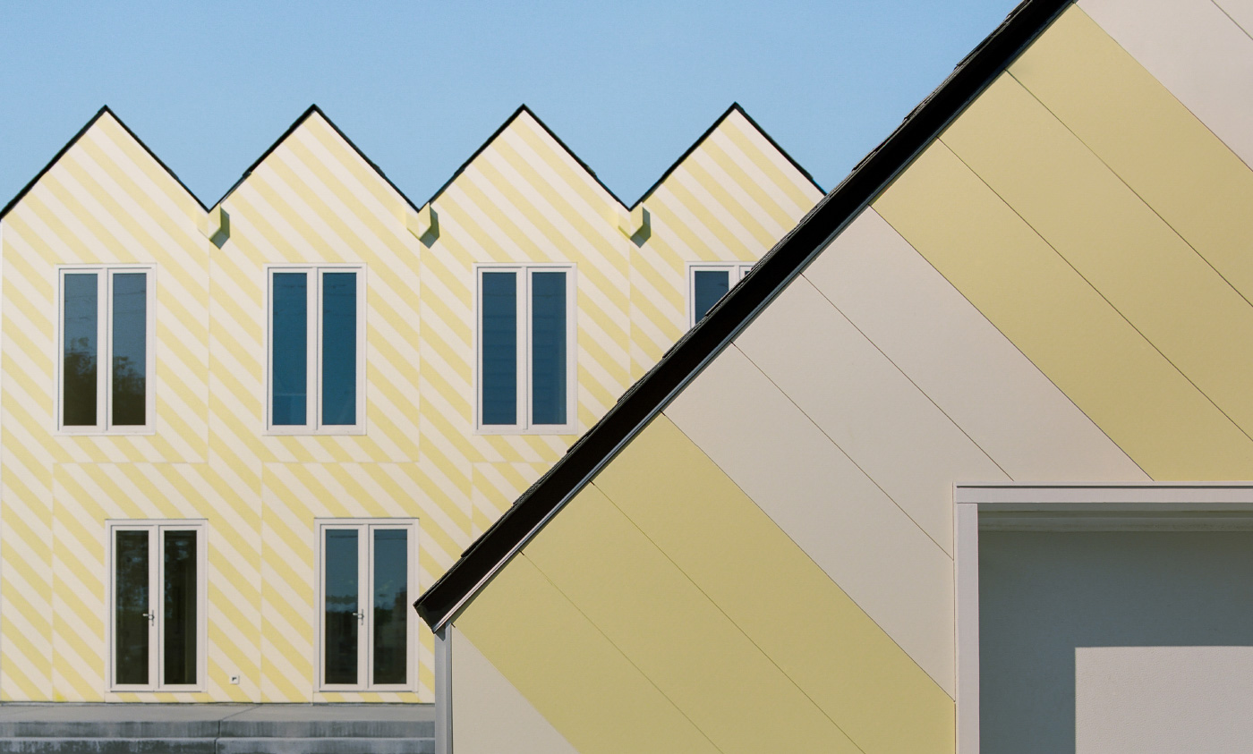 Exterior of a gabled house with yellow front designed by Independent Architecture