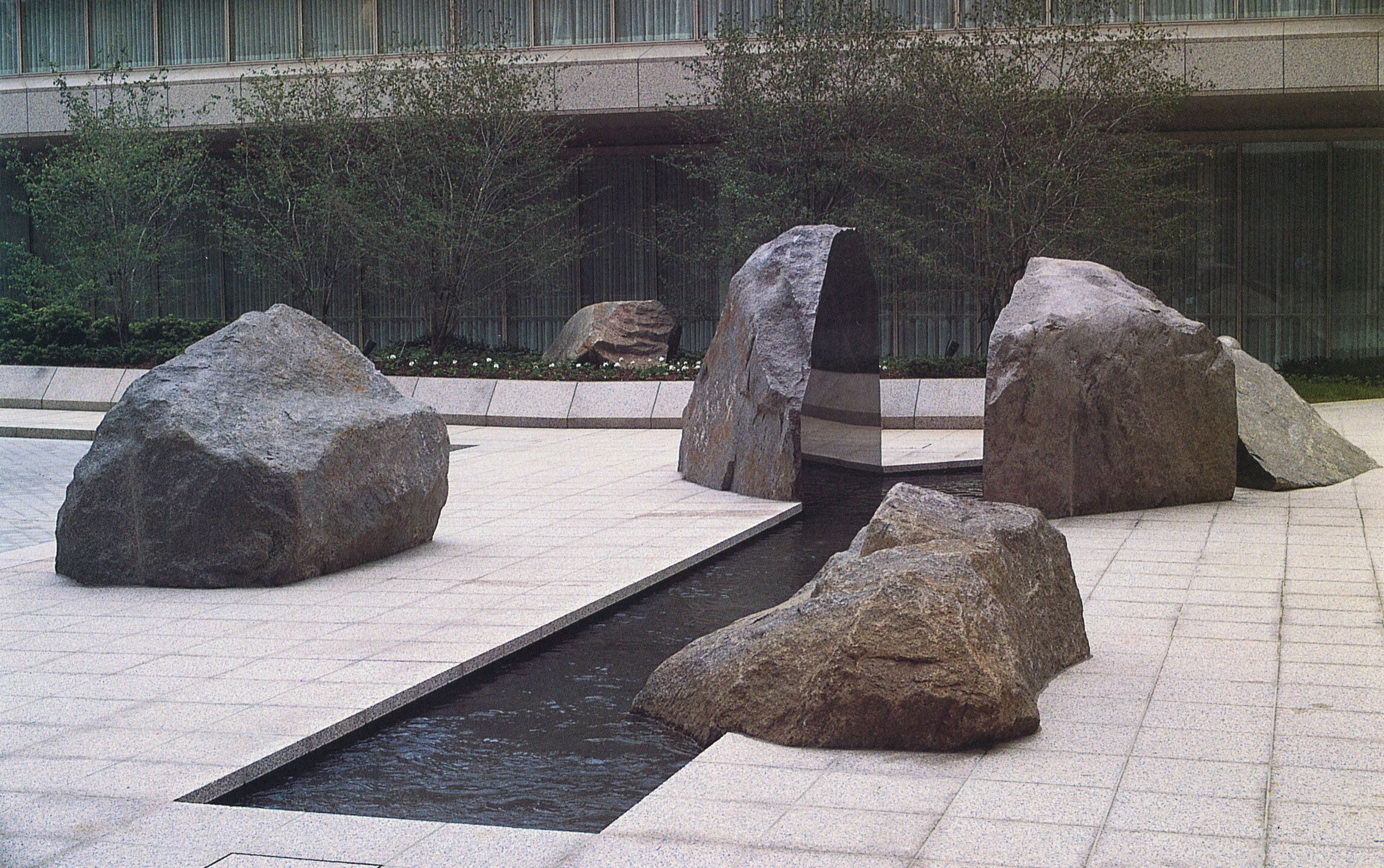 Exterior photo of the Marabar sculpture, split granite rocks, in a modernist courtyard