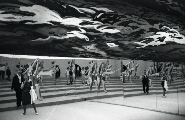 Black and white photo of people gathered beneath murals