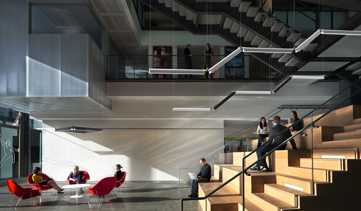 Interior of a multi-tiered office space with sittable stairs and modular lighting