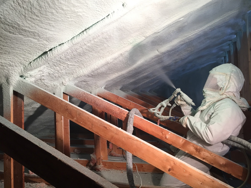 A man spraying Demilec insulation inside of a house