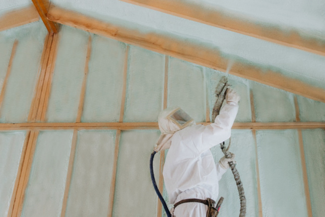 A man spraying insulation in a house