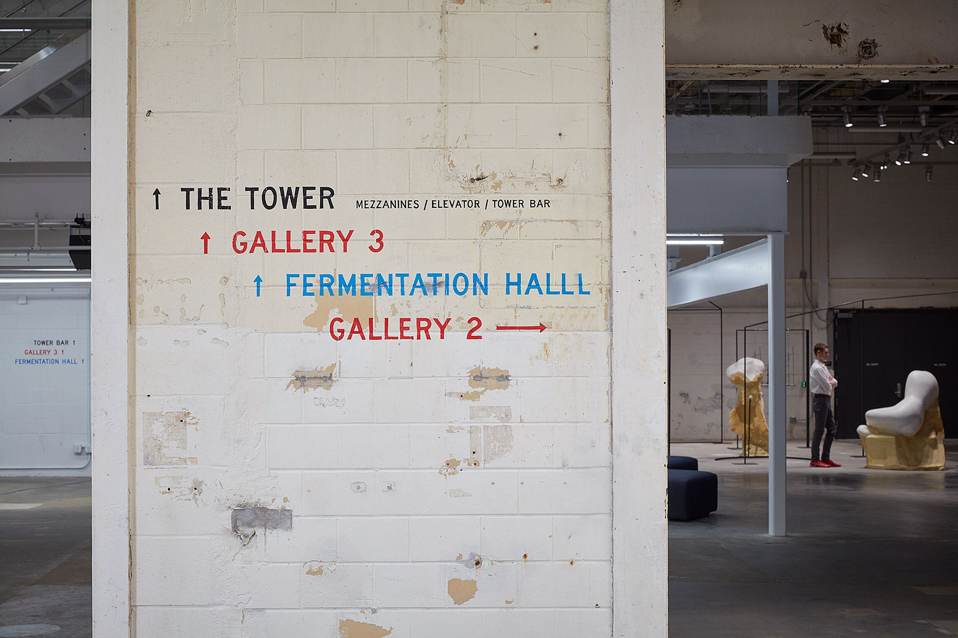 A sign on a brick wall leading to the tower, gallery 3, or the fermentation hall