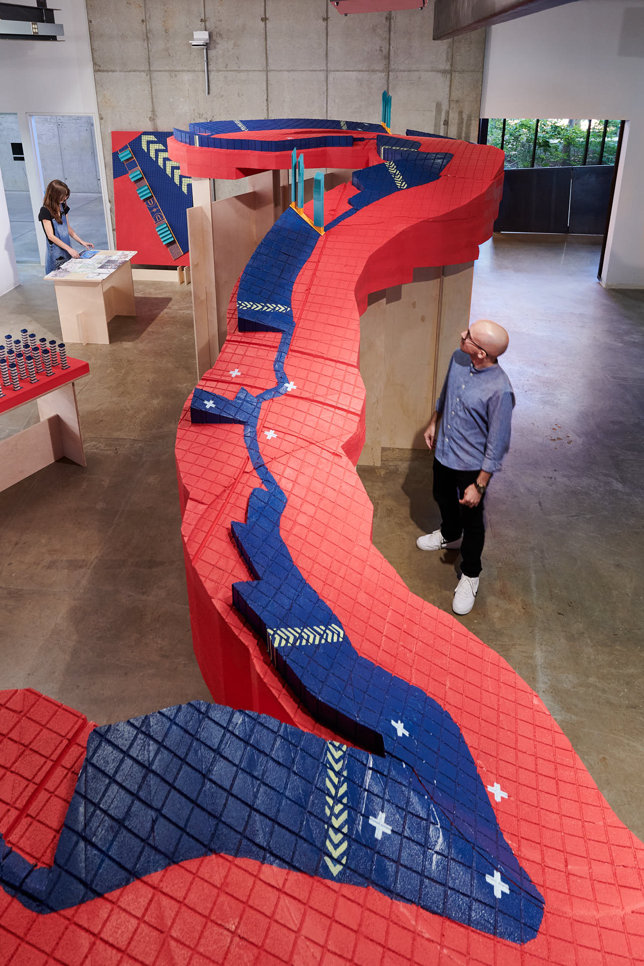 A long red and blue river installation with a man next to it