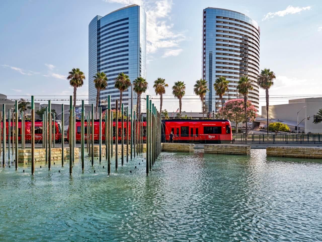 an urban pond with glass towers and palm trees