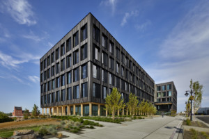 Photo of a dark five story building with a rectilinear massing
