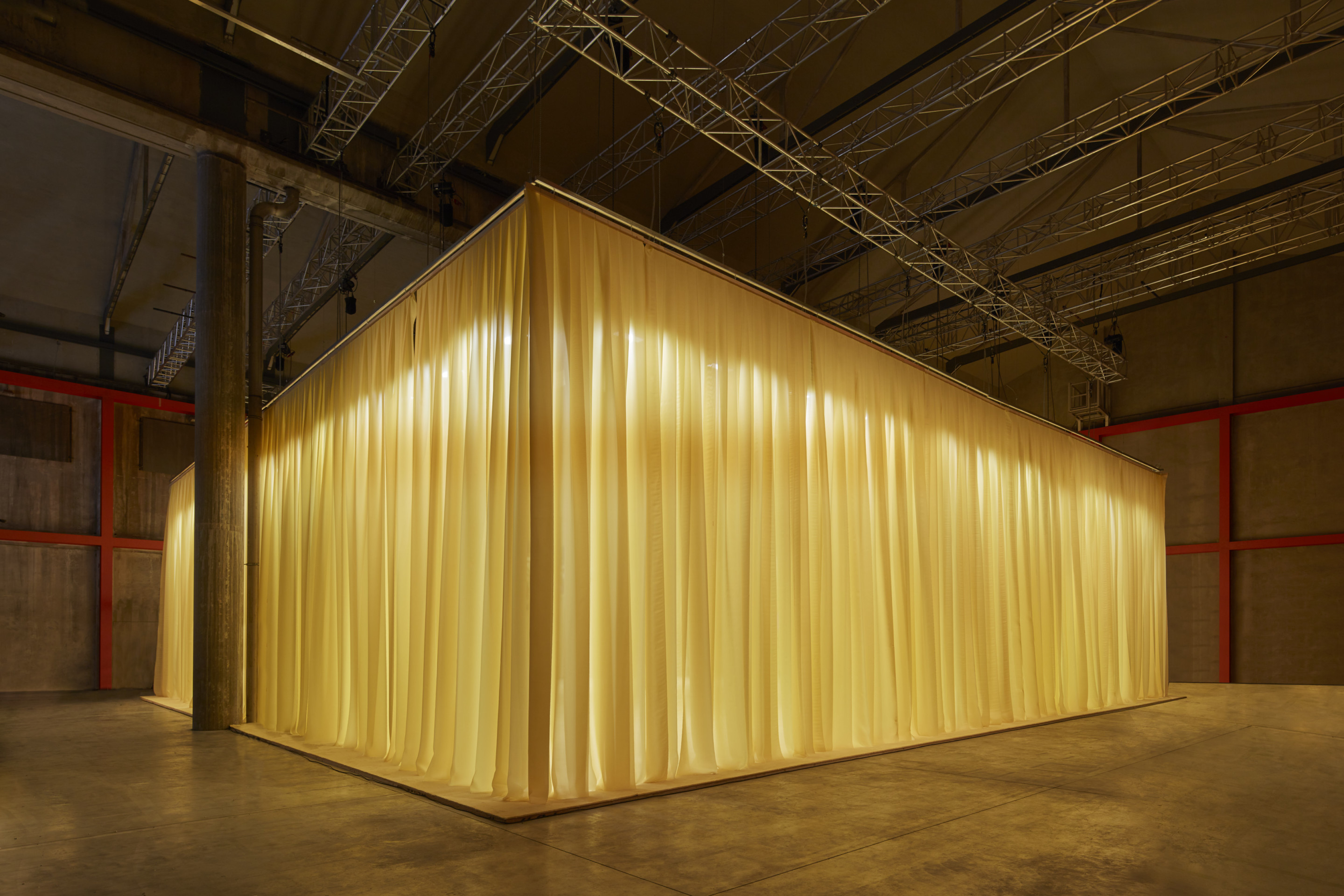 A yellow curtained area inside of a concrete arts space