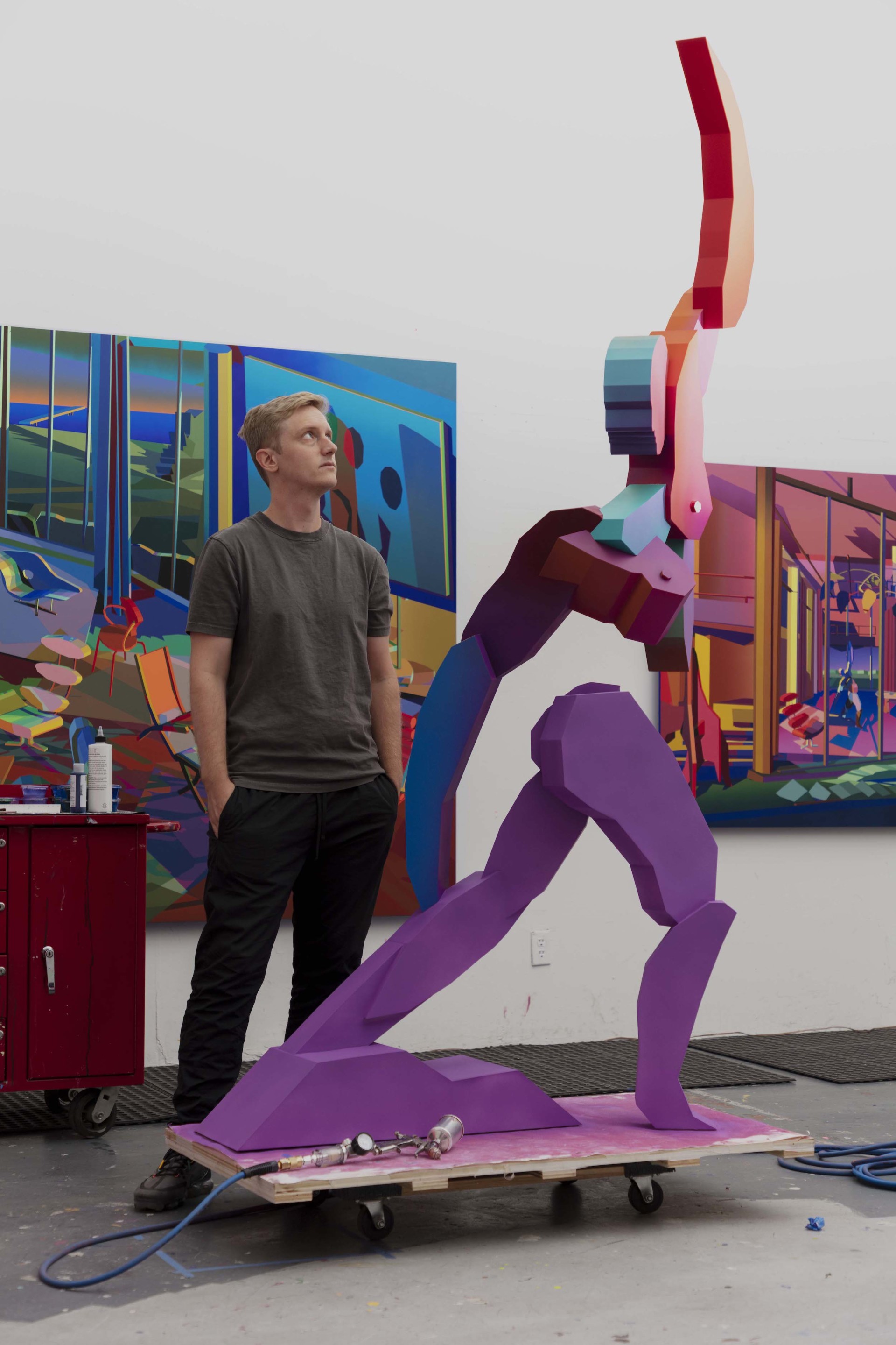 An artist next to a tall purple sculpture created for virtual window