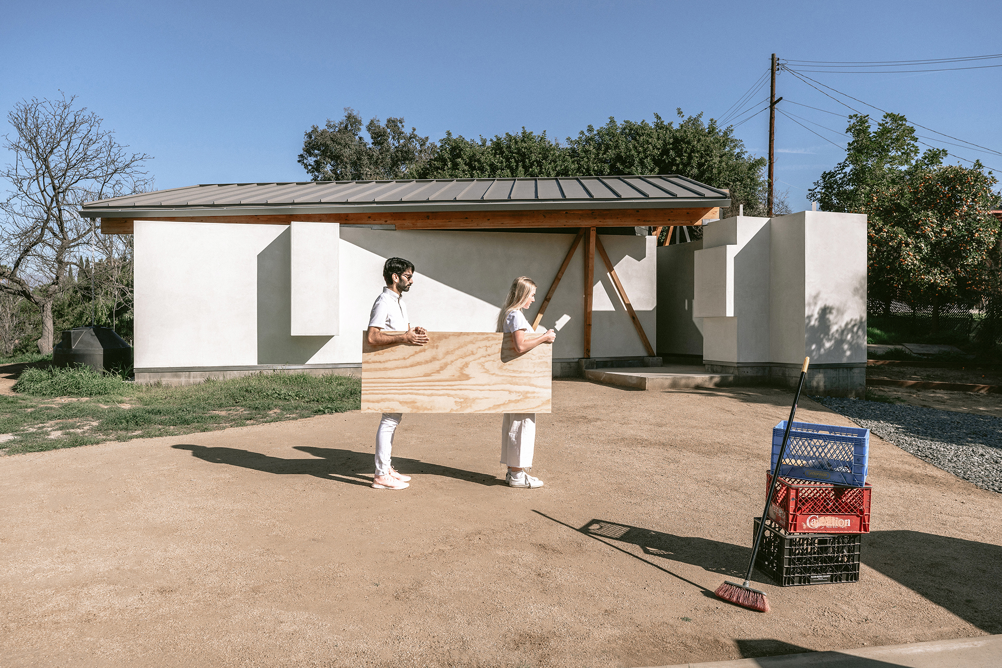 two people in white carrying plywood