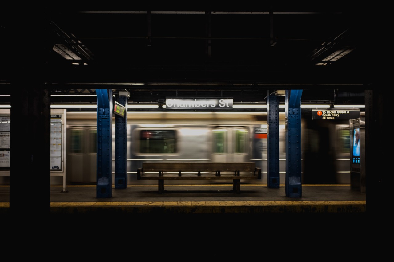 an mta station empty of people, with an empty train rolling through