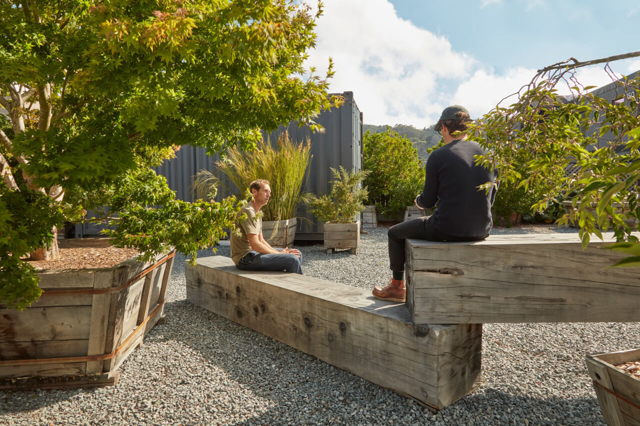 A landscape designed by terremoto with people sitting on wood planks