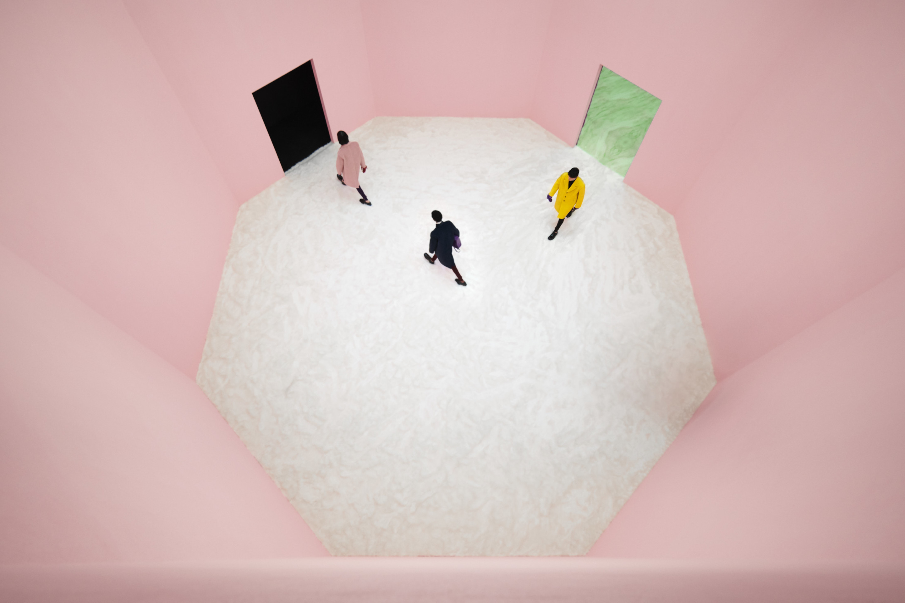 a pink room with three models trudging through at a 90 degree angle
