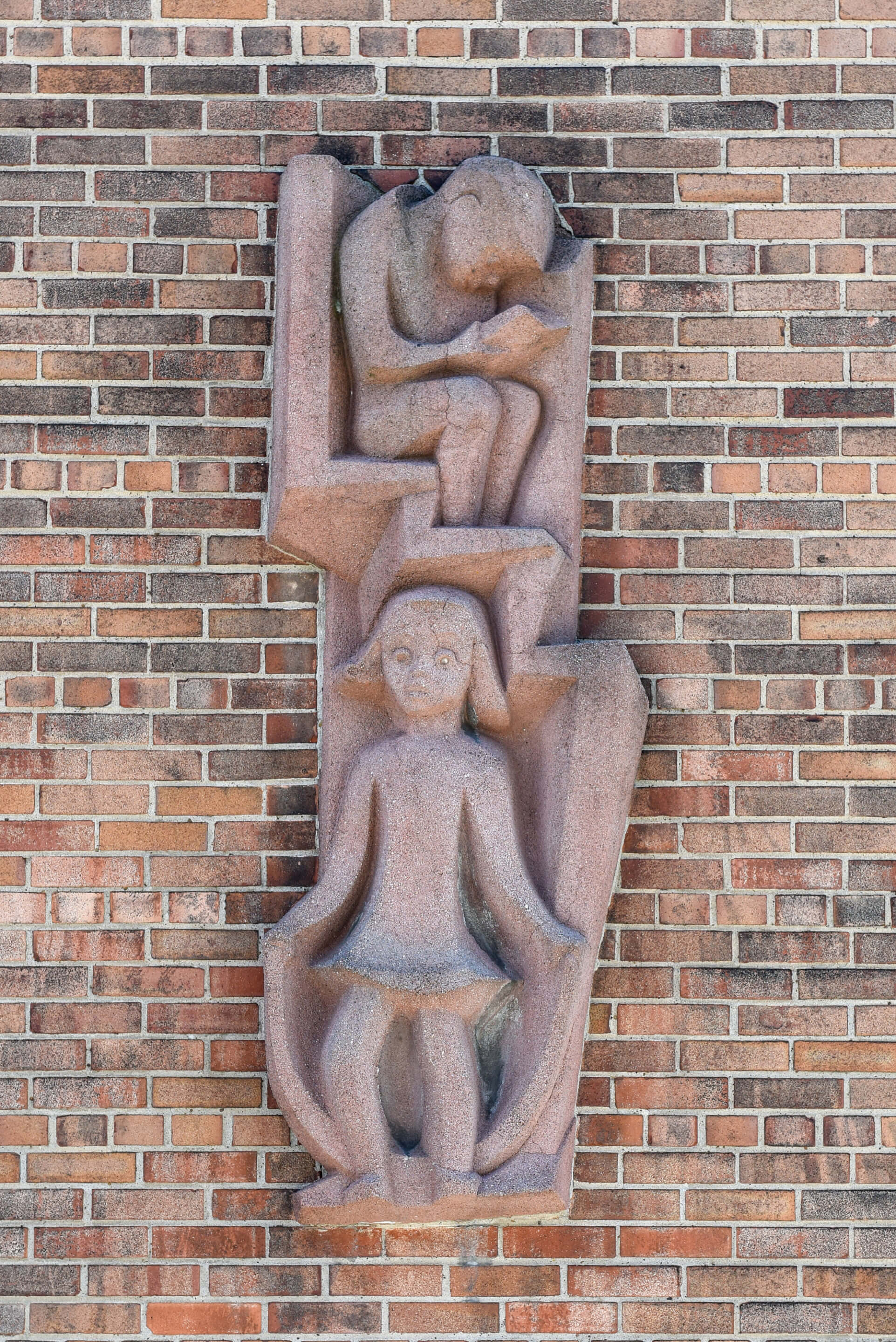 The brick facade of Willert Park with a woman and child jumping rope carved in concrete