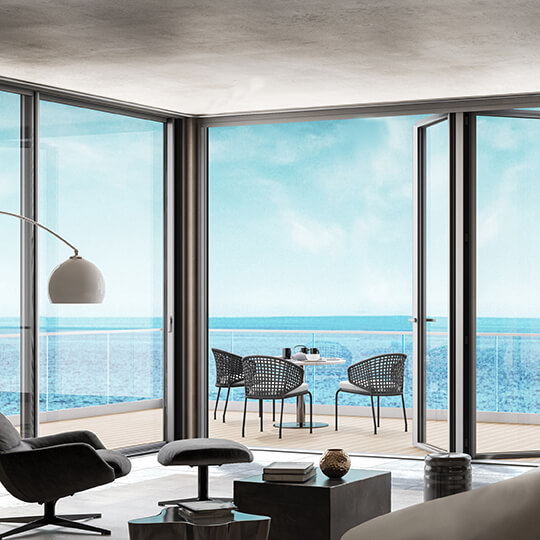 a living room and larger operable walls leading out onto a balcony with a body of water in the background