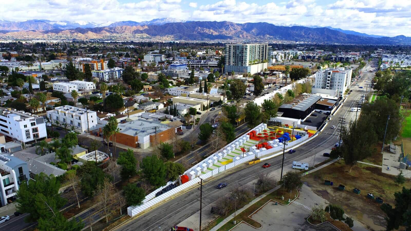 aerial view of brightly colored bridge housing community with mountains in background