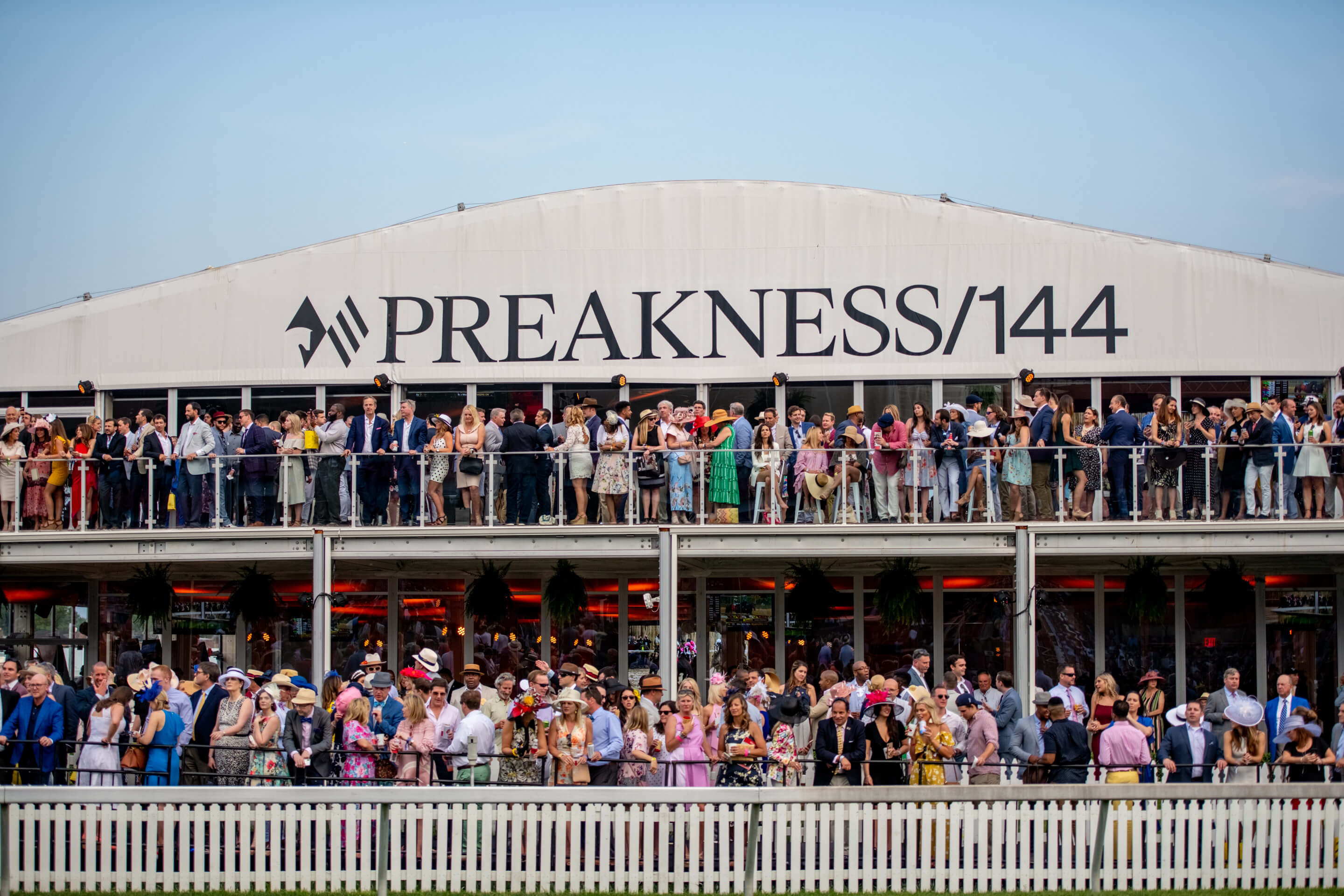 a large section of stands packed with people and a preakness 144 sign above