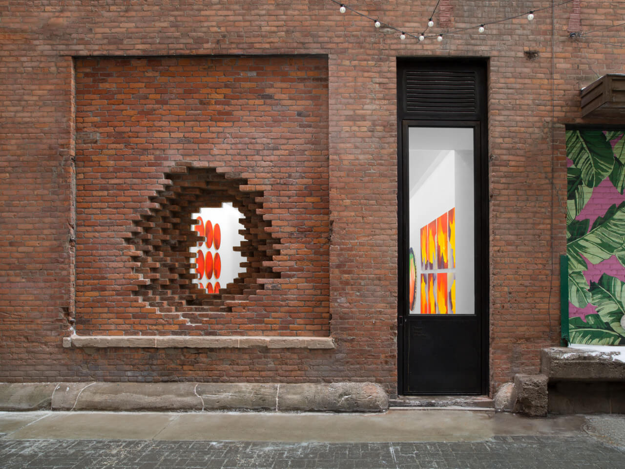 view inside of an art gallery through a brick portal leading to Library Street Collective