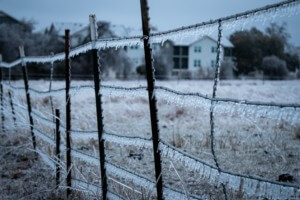 image of a frozen texas iced out after a storm, with icicles on a barbed cattle fence