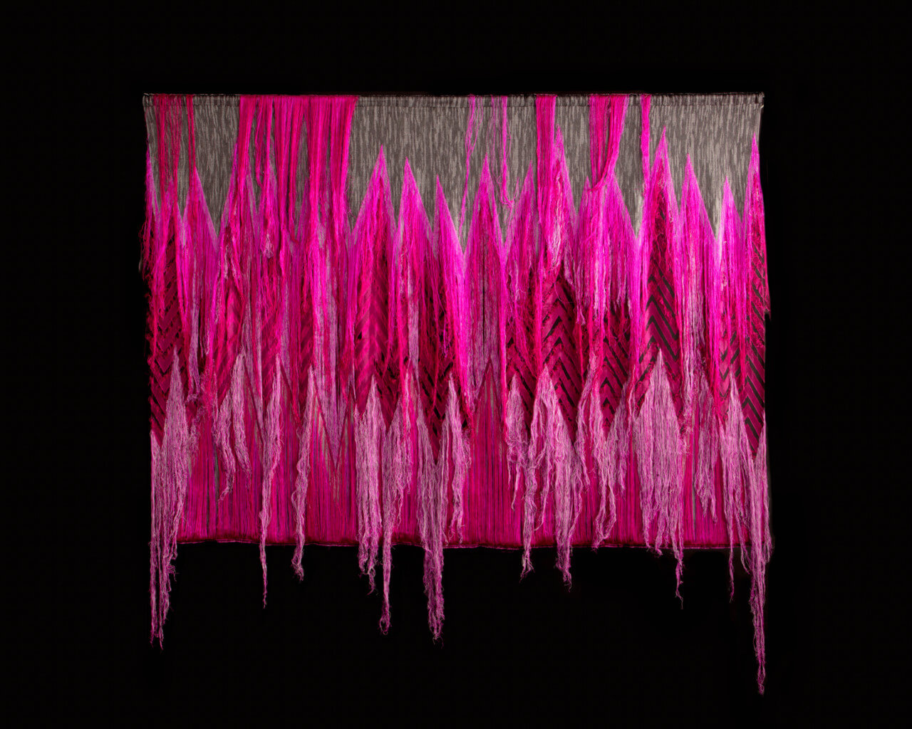 a pink tapestry with hanging threads