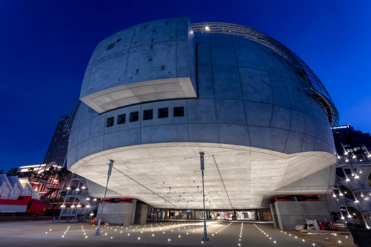 nighttime photograph depicting a concrete half-dome that cantilevers over a walkway