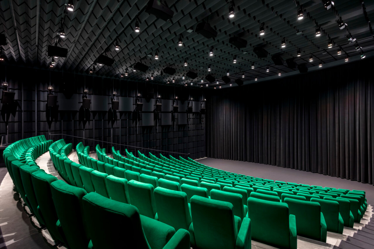 a darkened theater space with green seats