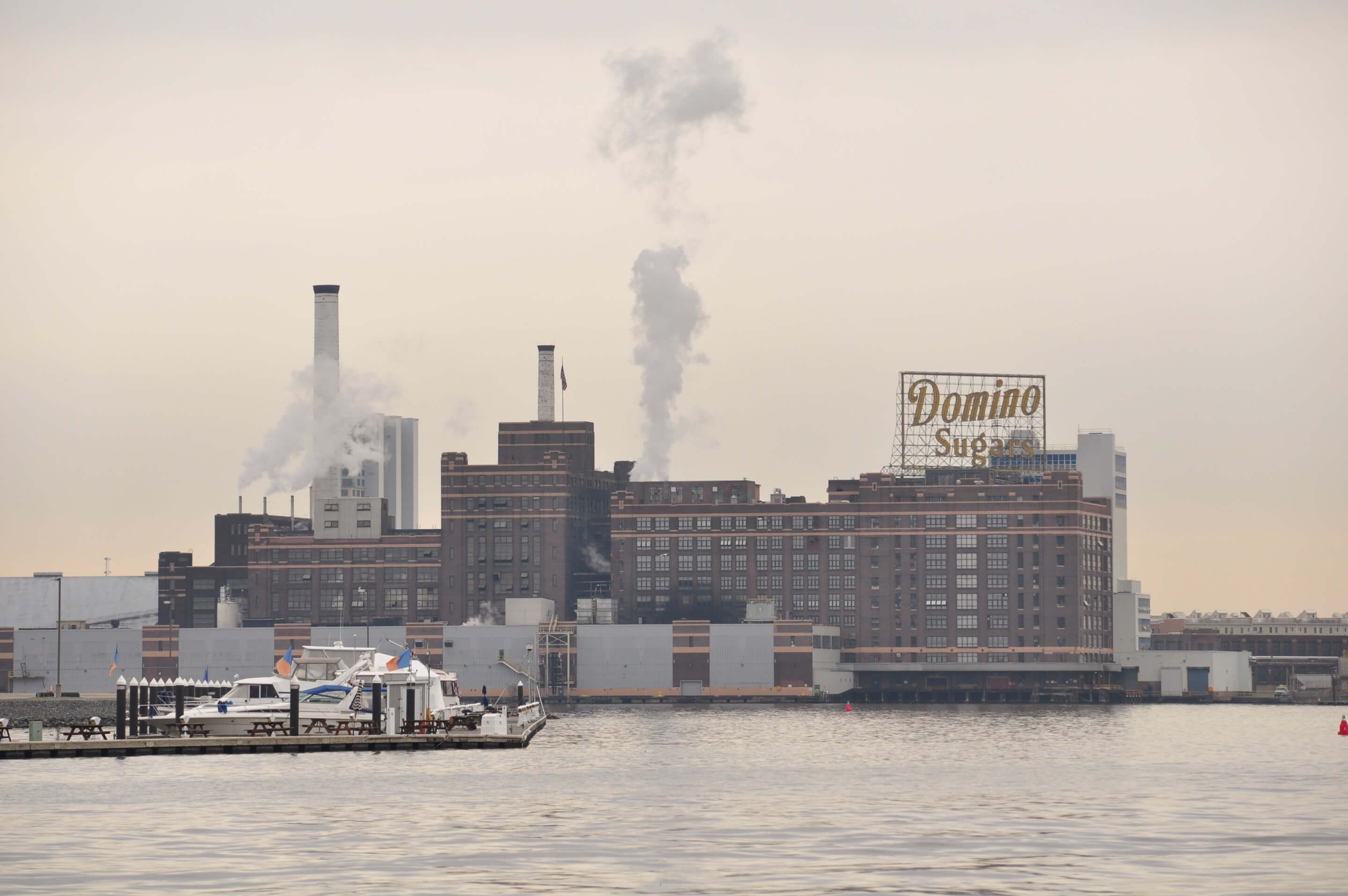 looking at a factory with the domino sugars sign from the harbor