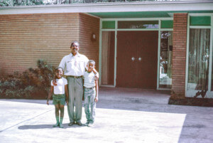 photograph depicting a smiling man and his two sons in the front of a modern midcentury house in Houston, john s. chase