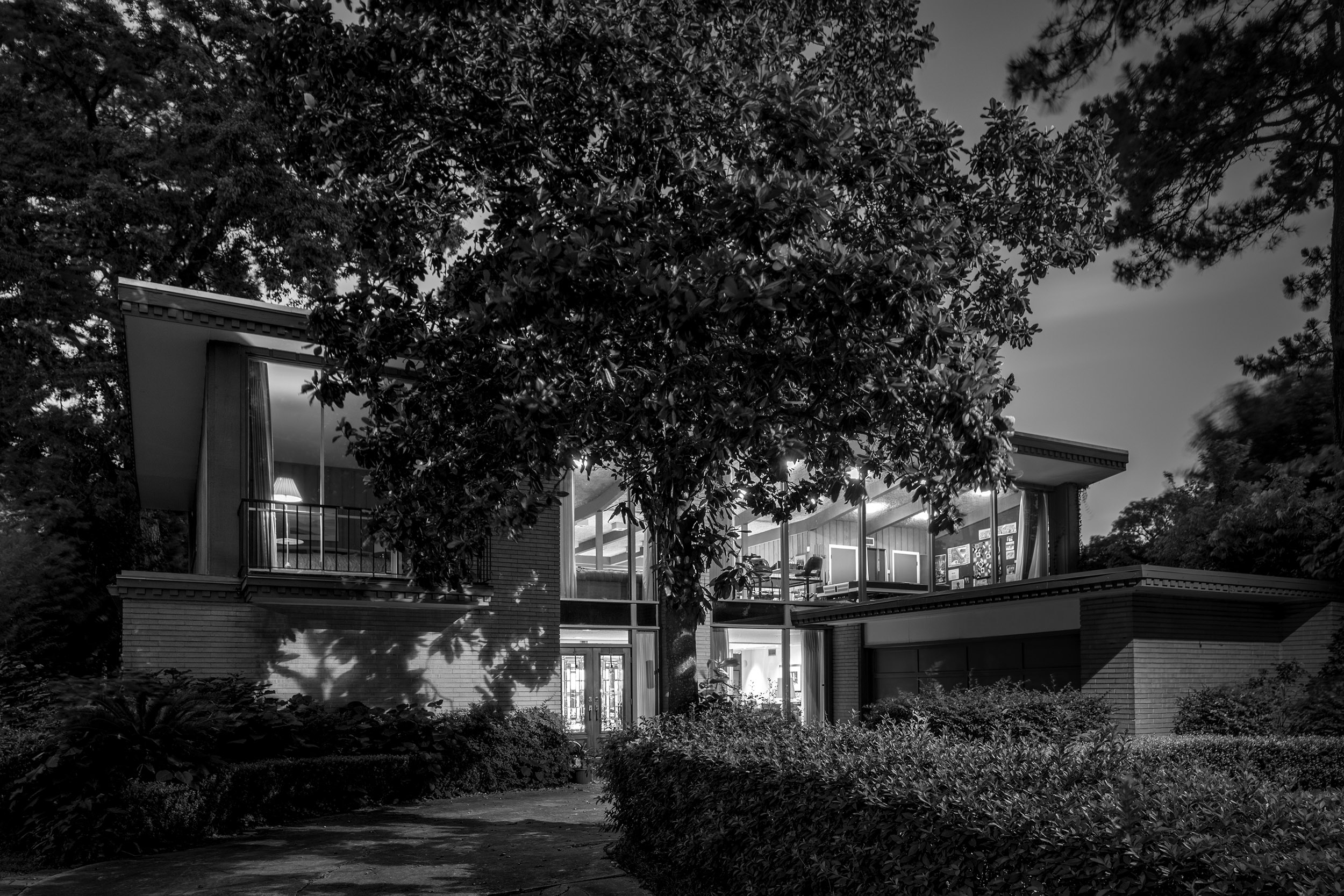 black-and-white photograph depicting a two-story midcentury modern house in Houston with tree in the foreground