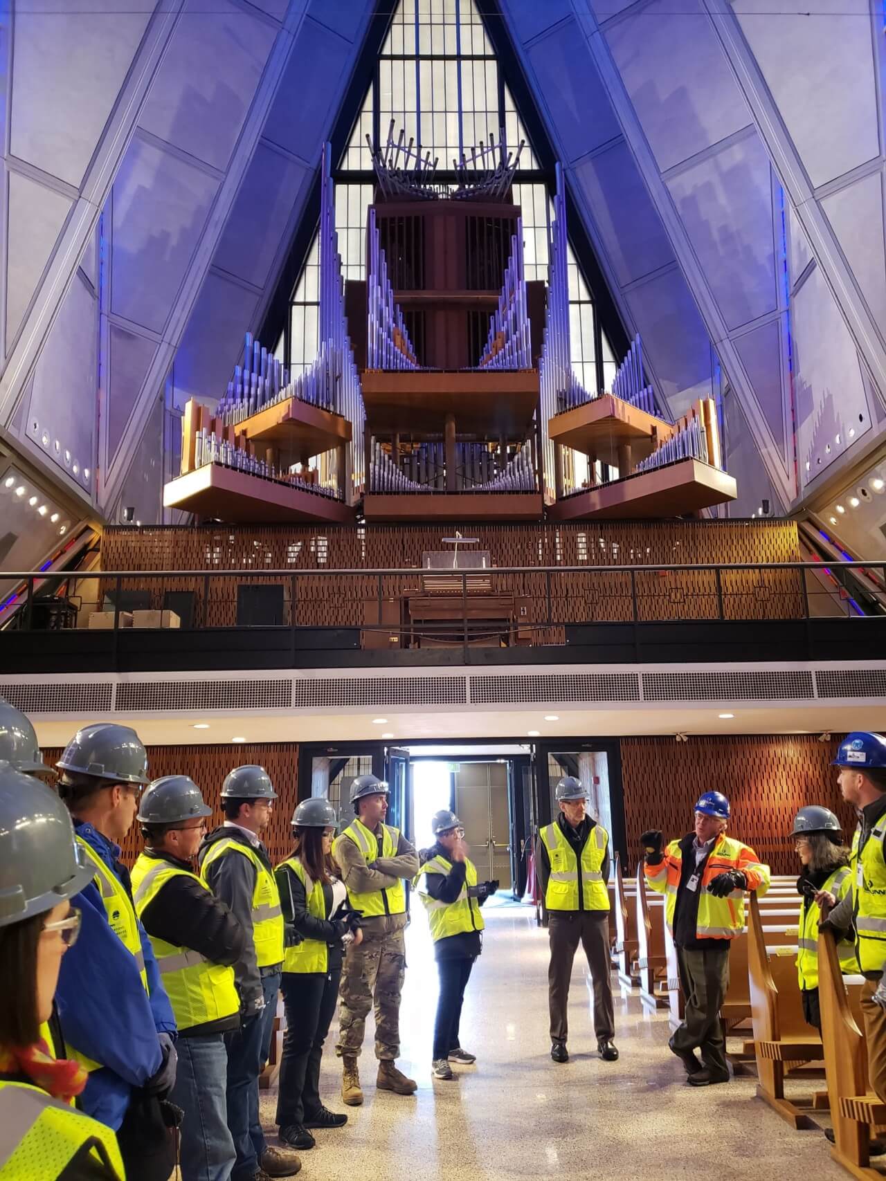 a group of construction workers gathered below the arches of the air force cadet chapel