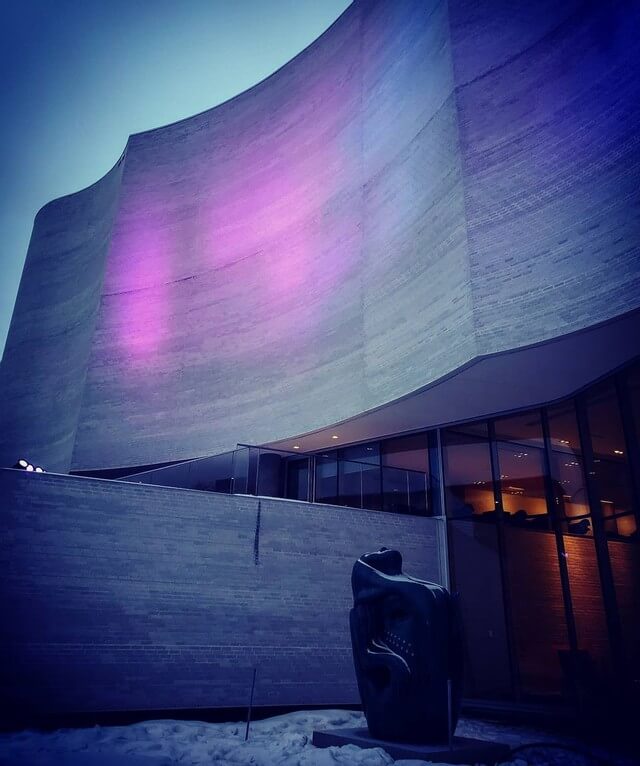 the curving concrete facade of the qaumajuq with blue and purple light projections splashed across it