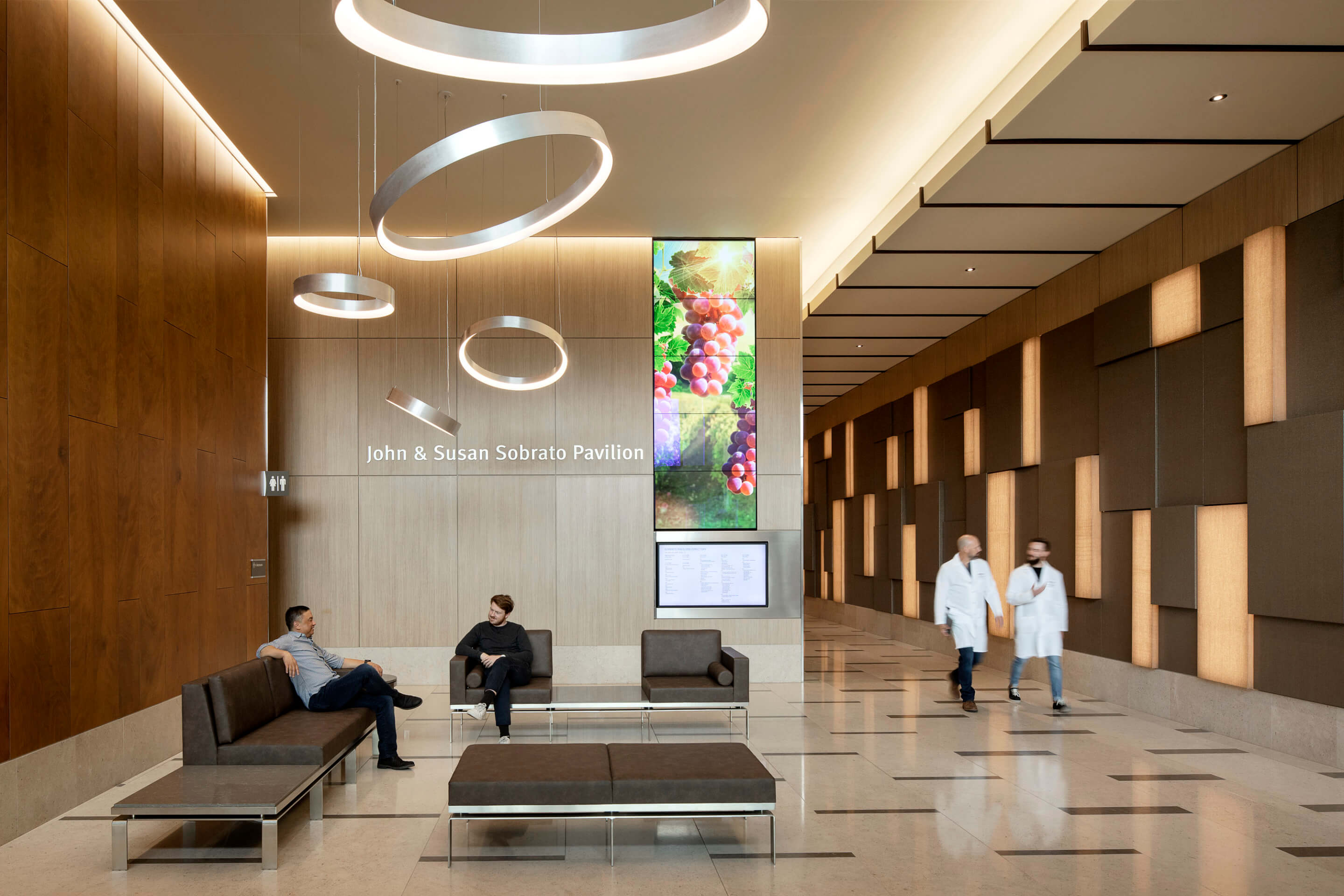 Interior of the el camino health lobby with people waiting below tilted circular lights and wood paneled walls