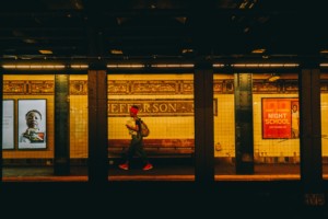 A woman walking across a nyc subway platform, which avoided transit cuts