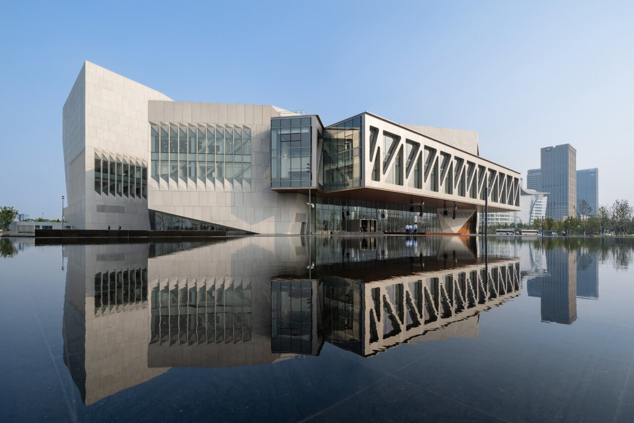 A concrete school hovering over a reflecting pool