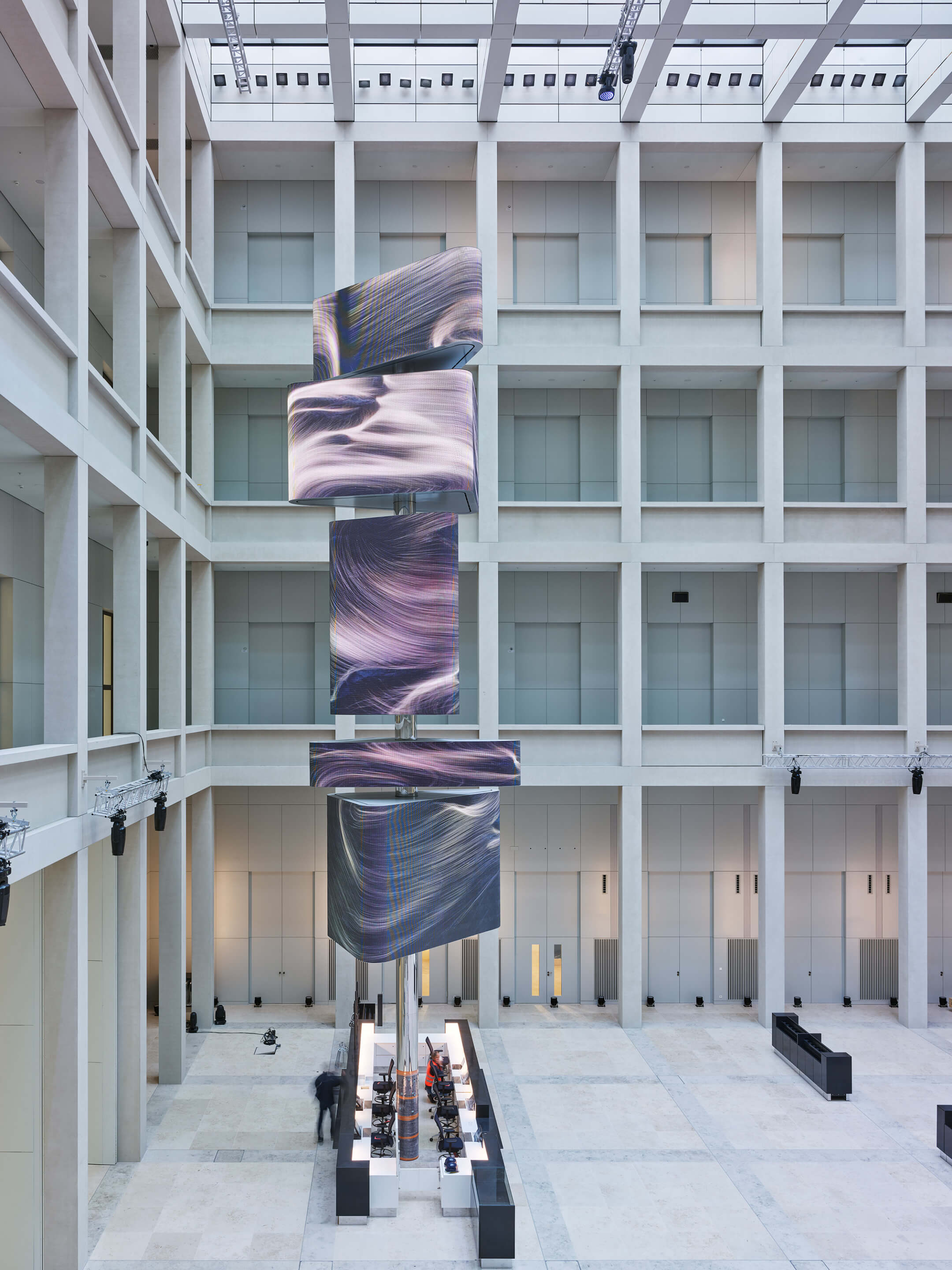 Installation view of a multistory arrangement of purple banners against a modernist gallery foyer