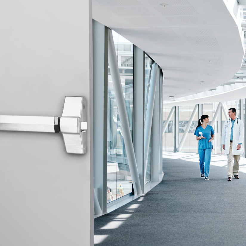 two doctors walking down a curved hallway with a door and door handle to the side