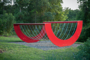 a red steel sculpture invoking a rocker designed by Melvin Edwards