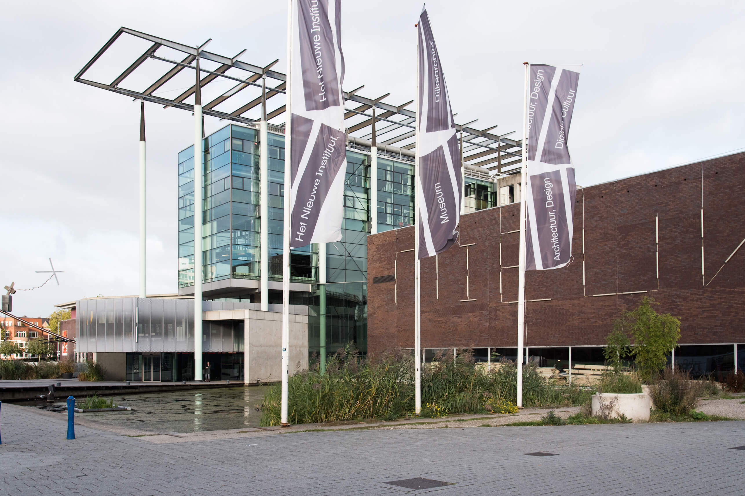Exterior of a glassy box building with scaffolding and purple flags