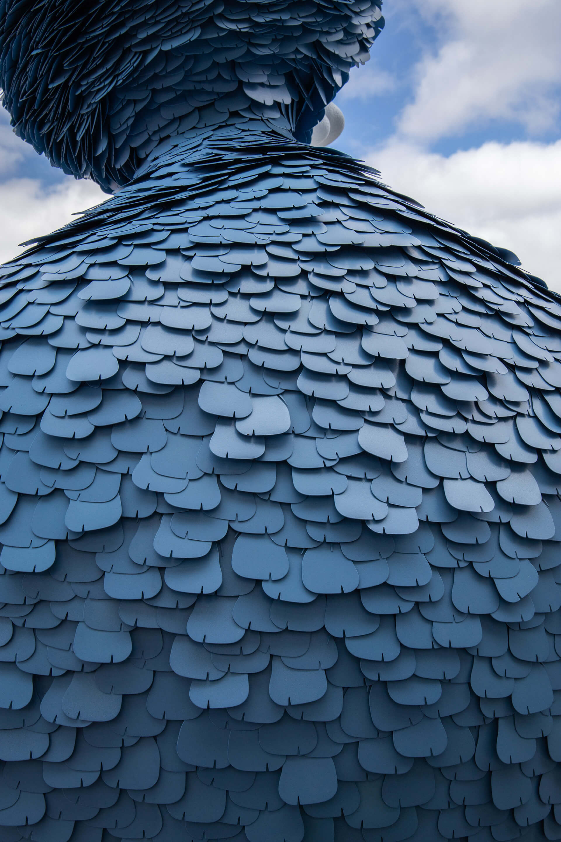 close up detail of a big bird statue made from blue metal shingles