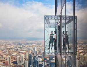 People hanging out over a glass box