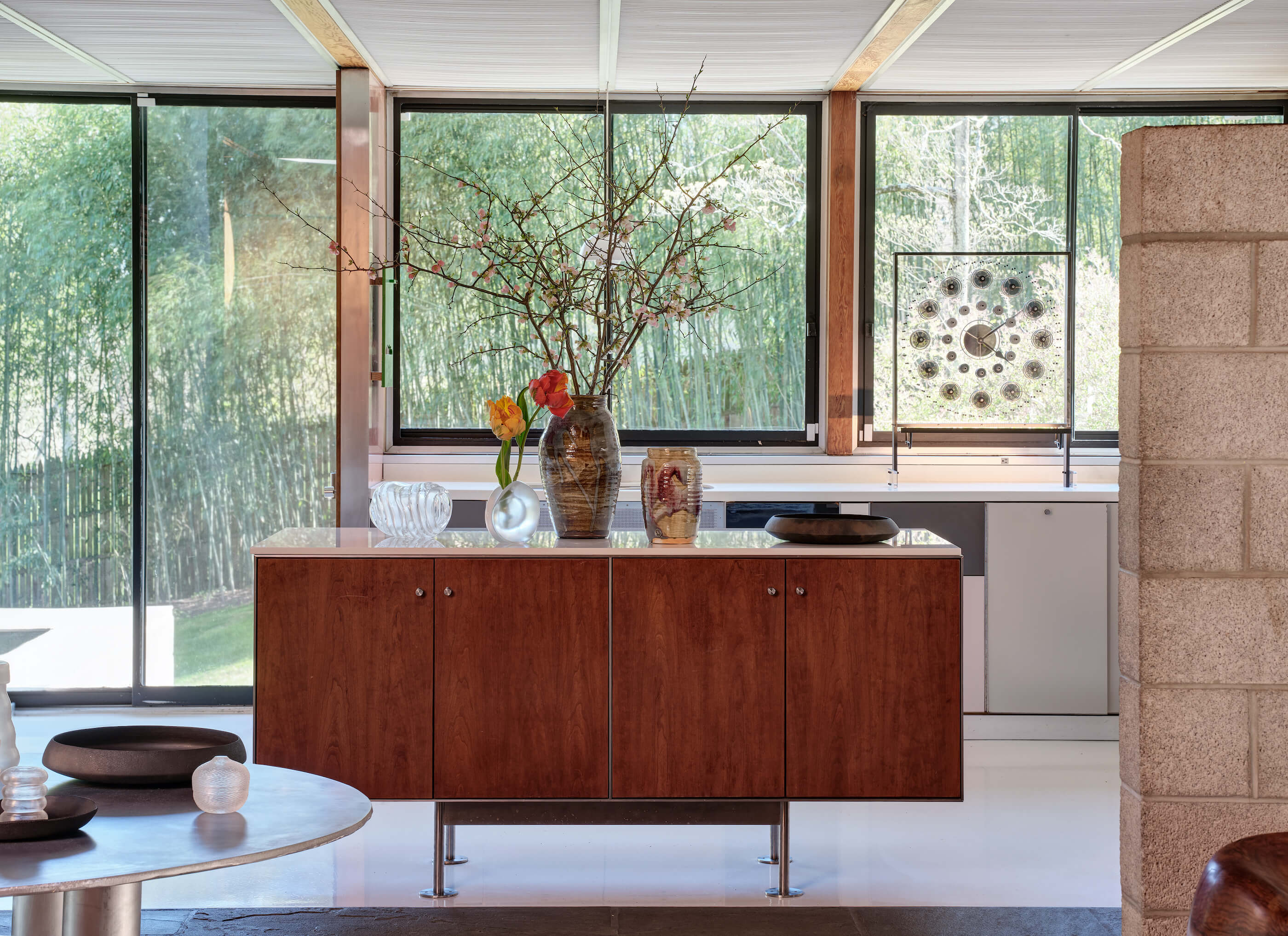 a mid-century credenza in a kitchen topped by ceramics and decorative objects